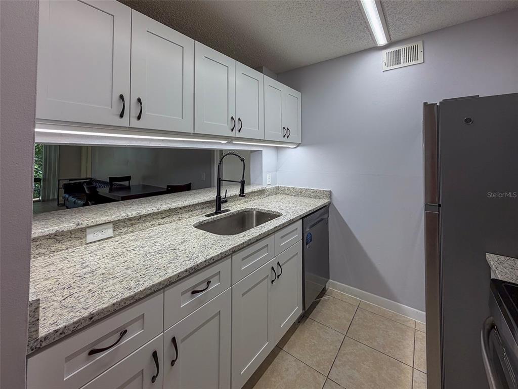 3921 Southwest 34th Street, Unit 301 Gainesville, FL 32608 - Photo 5 of 31 a kitchen with stainless steel appliances granite countertop a sink and a white cabinets