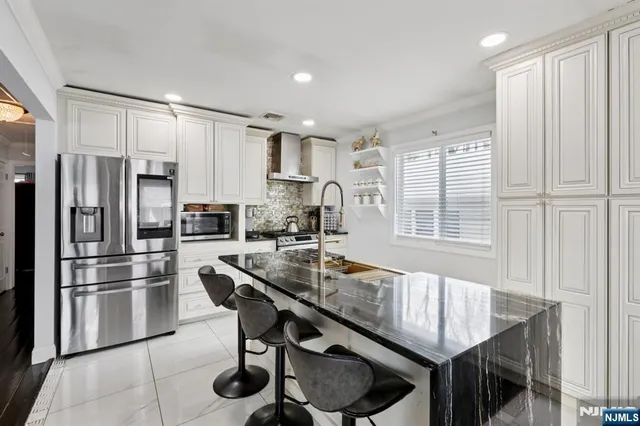 a kitchen with stainless steel appliances granite countertop a refrigerator a sink dishwasher a stove and a refrigerator