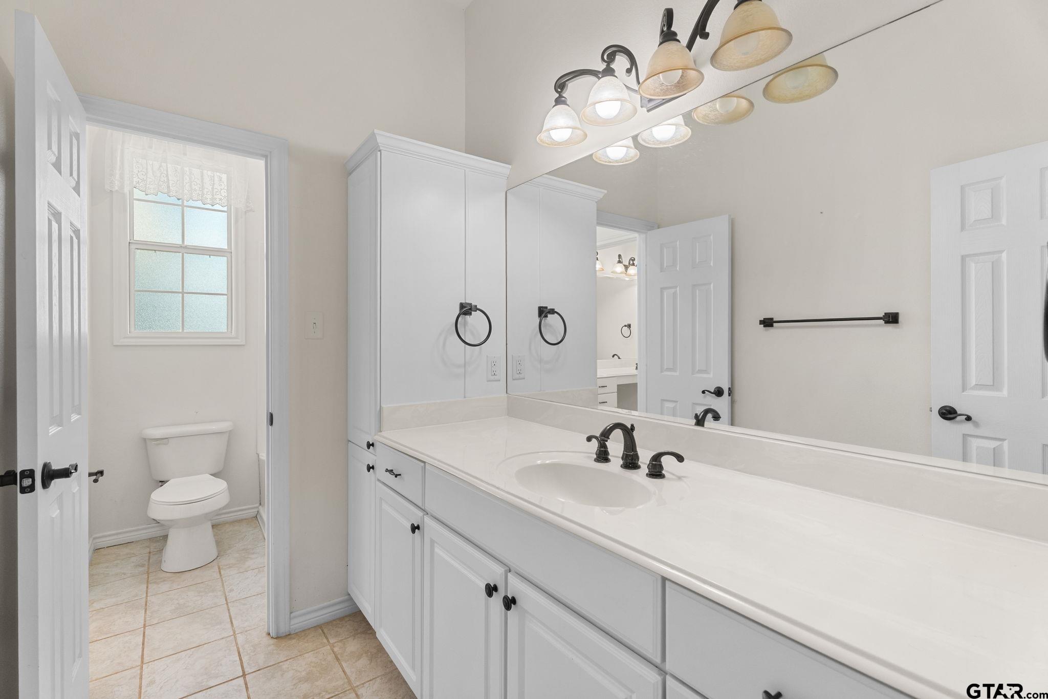 7031 Ridge Pl Circle Tyler, TX 75703 - Photo 18 of 27 a bathroom with a sink a toilet and a mirror