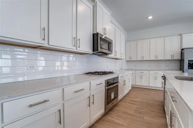 a kitchen with stainless steel appliances granite countertop white cabinets a sink and dishwasher