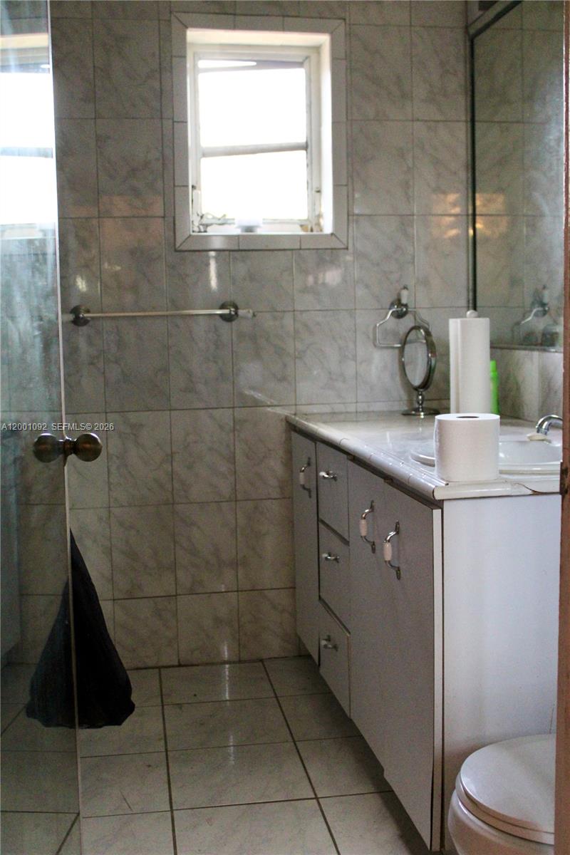 111 Northwest 52nd Street Miami, FL 33127 - Photo 5 of 14 a bathroom with a granite countertop sink a toilet and a mirror