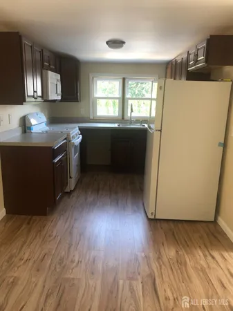 a kitchen with a wooden floor and white stainless steel appliances
