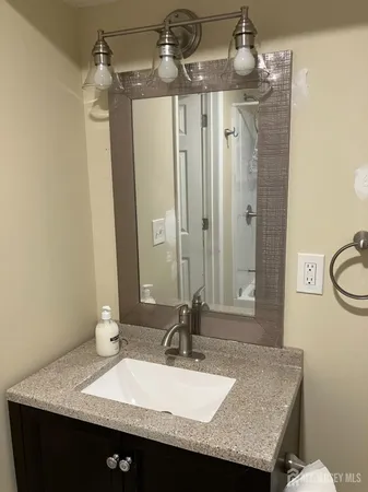 a bathroom with a granite countertop sink a mirror and shower