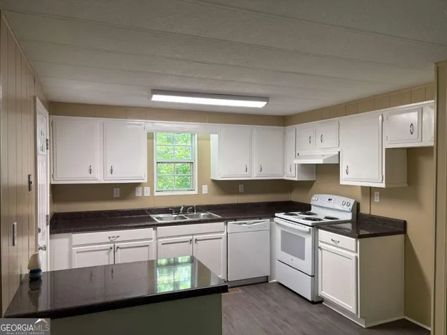 a kitchen with granite countertop white cabinets and white appliances