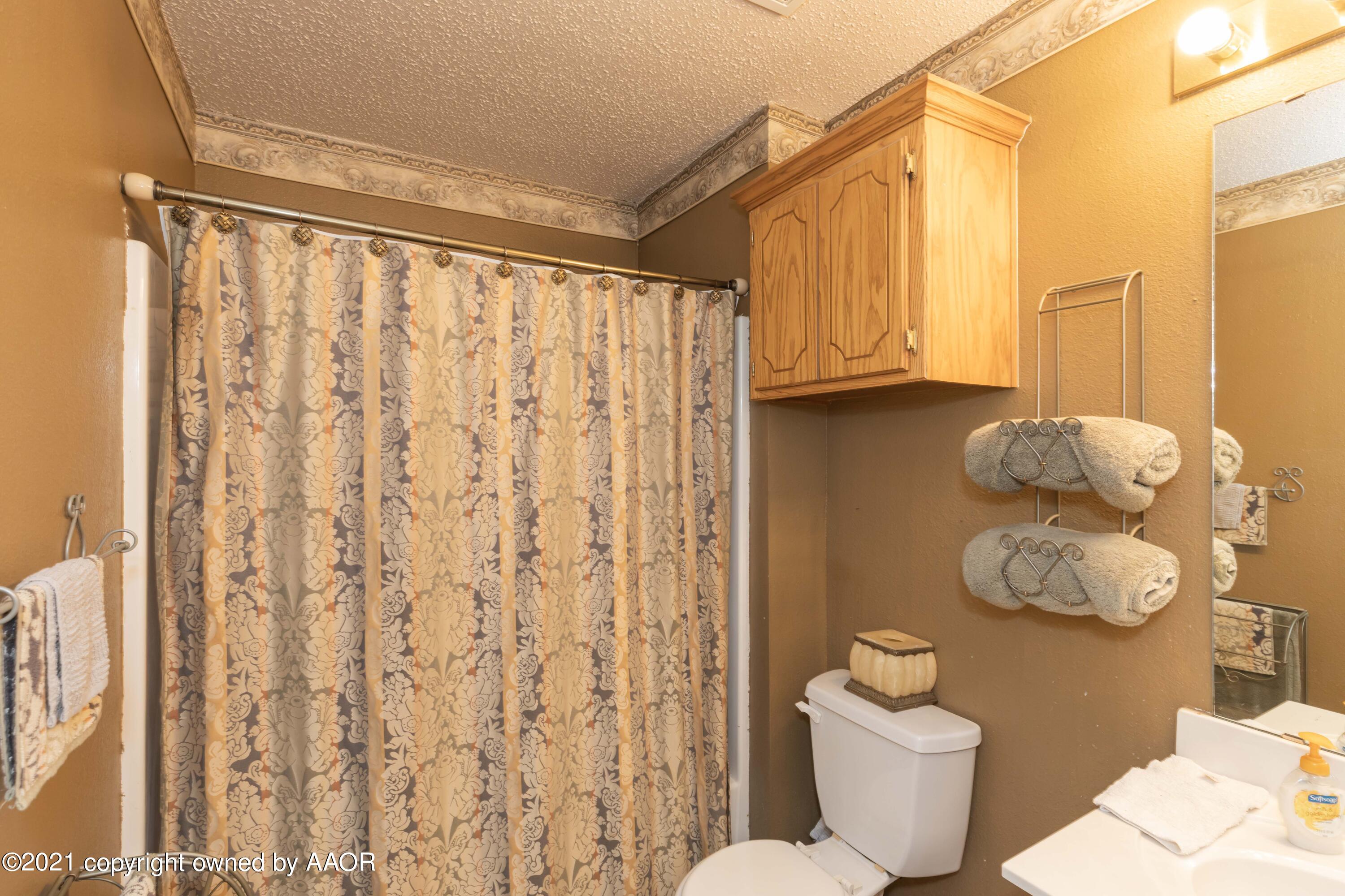 1025 Ketler Street Amarillo, TX 79104 - Photo 18 of 31 a bathroom with a toilet a sink and a shower curtain