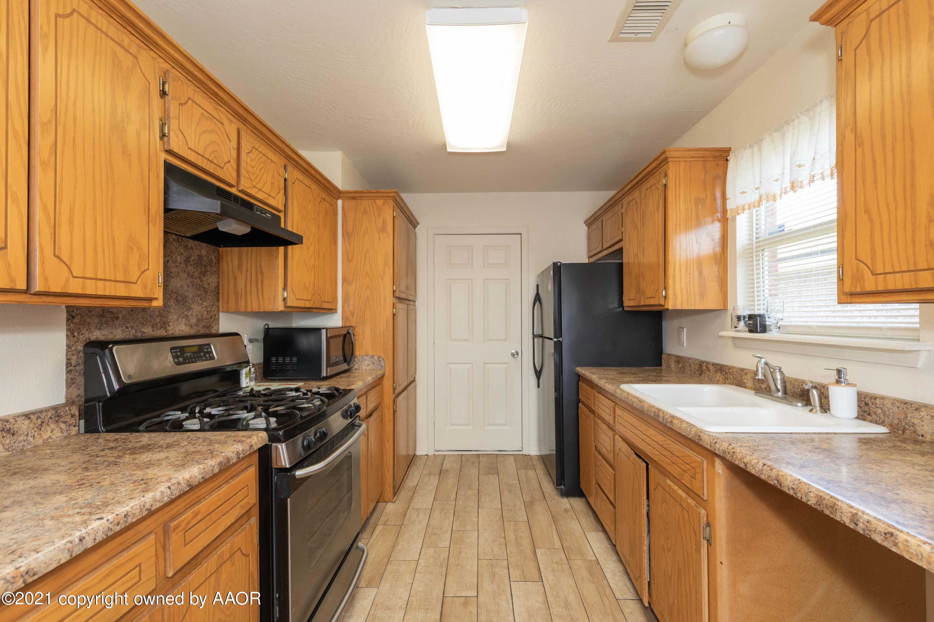 1025 Ketler Street Amarillo, TX 79104 - Photo 8 of 31 a kitchen with stainless steel appliances a sink cabinets and wooden floor