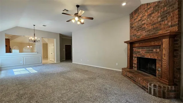 an empty room with windows fireplace and fan