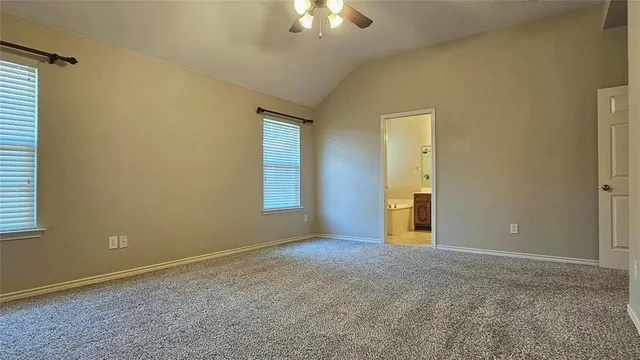 an empty room with a chandelier fan and windows