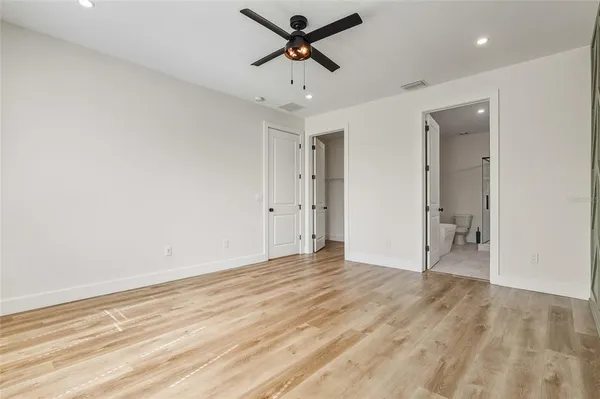 a view of empty room with wooden floor and fan