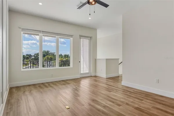 a view of empty room with wooden floor and fan