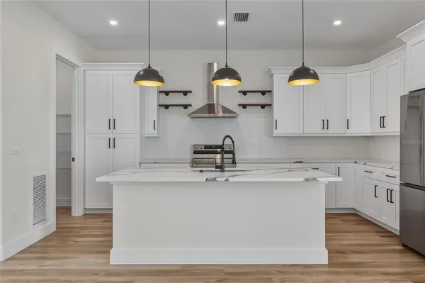 a kitchen with stainless steel appliances granite countertop a sink a stove and a wooden floors