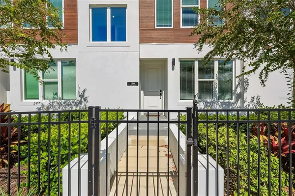 a view of a house with a small yard and large trees
