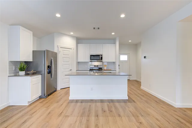 a kitchen with stainless steel appliances granite countertop a refrigerator stove top oven and sink