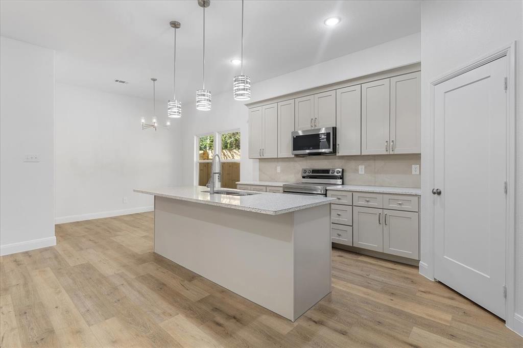 4715 Ramey Avenue Fort Worth, TX 76105 - Photo 7 of 32 a kitchen with kitchen island a stove a sink a center island and a window