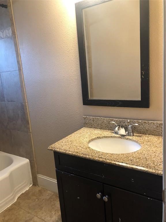 5631 Groveton Street Houston, TX 77033 - Photo 11 of 13 a bathroom with a granite countertop sink and a mirror
