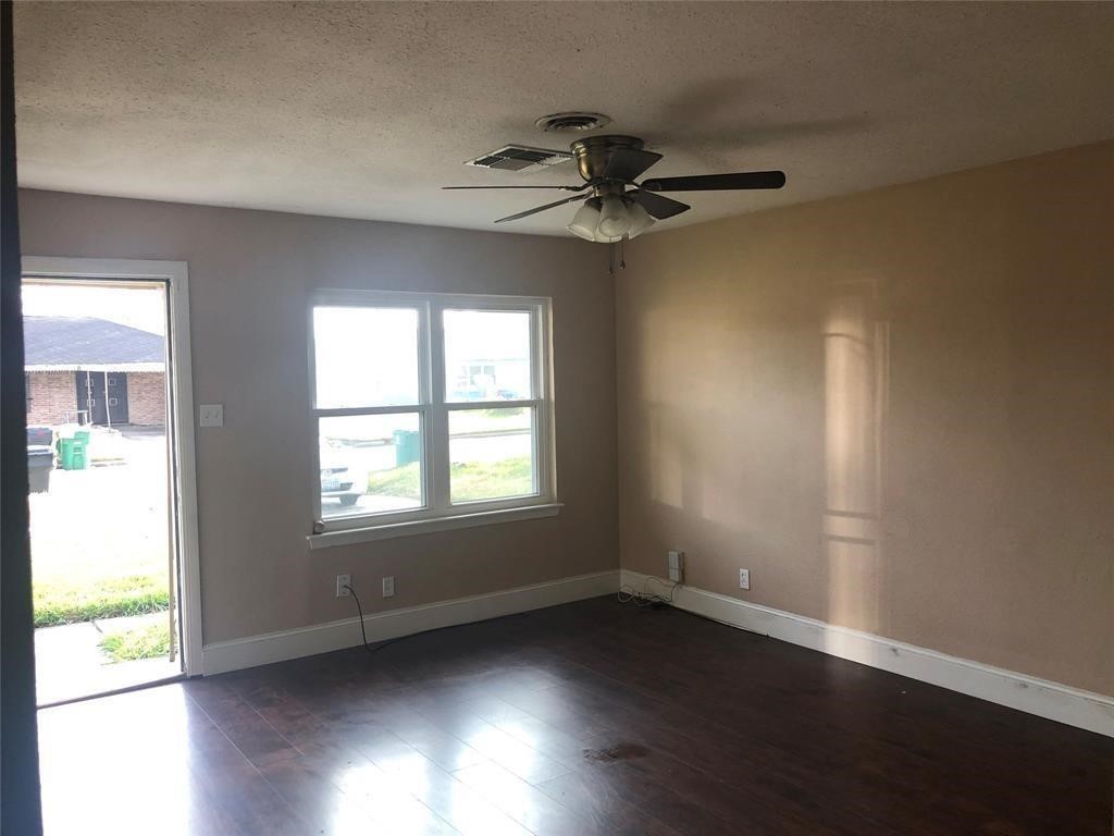 5631 Groveton Street Houston, TX 77033 - Photo 4 of 13 an empty room with wooden floor fan and windows