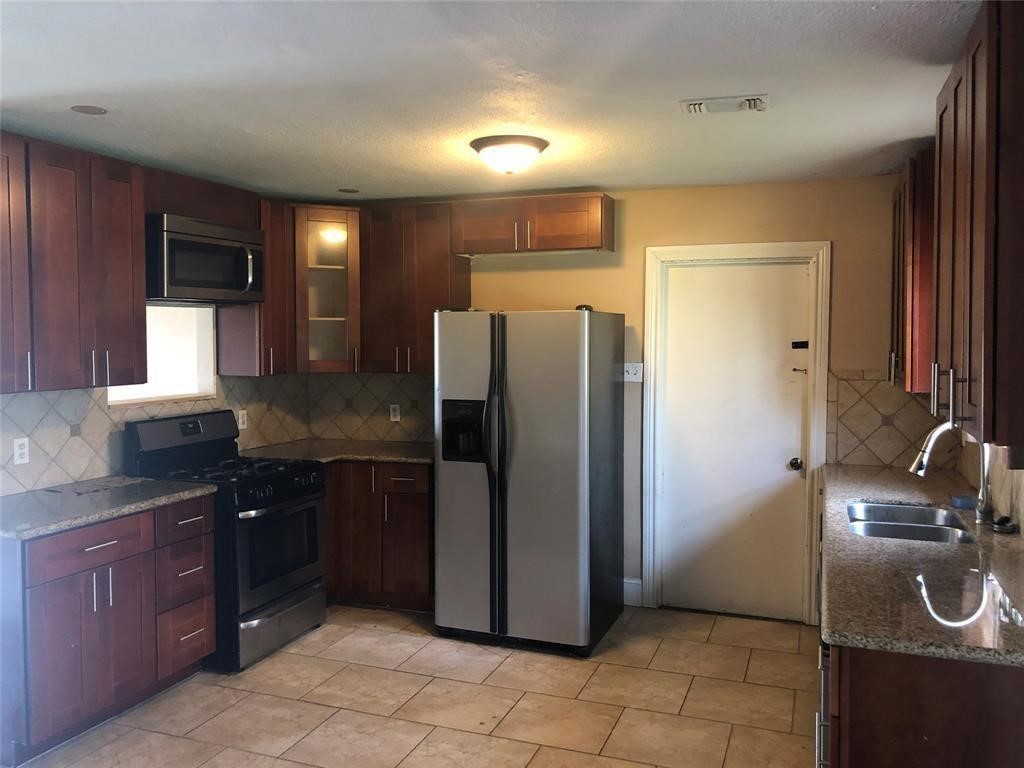 5631 Groveton Street Houston, TX 77033 - Photo 6 of 13 a kitchen with a refrigerator and a sink