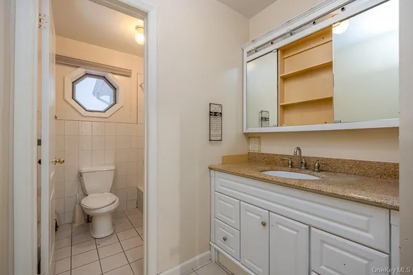 a bathroom with a granite countertop toilet sink and mirror