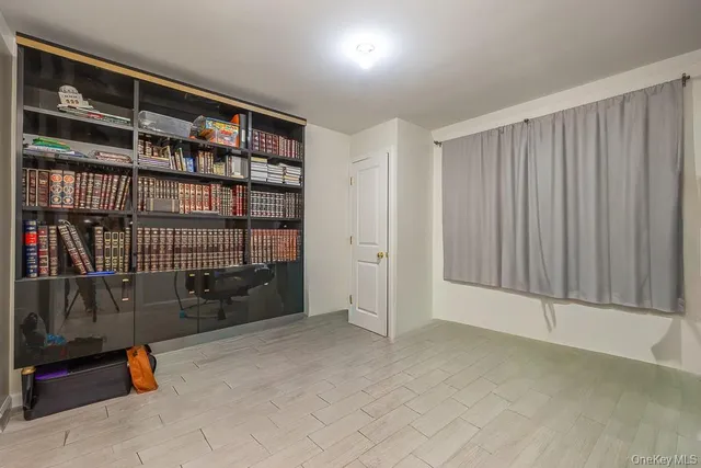 a view of an empty room with wooden floor and a book shelf