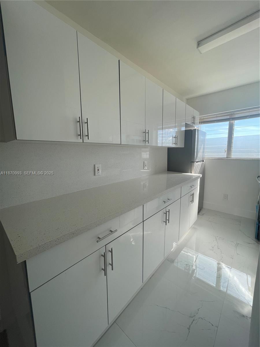 785 81st Street, Unit 3 Miami Beach, FL 33141 - Photo 4 of 12 a kitchen with white cabinets and white appliances