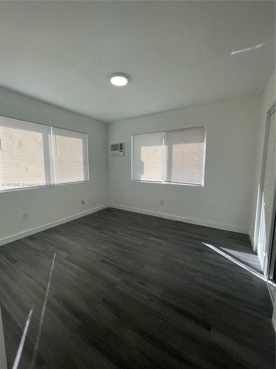 785 81st Street, Unit 3 Miami Beach, FL 33141 - Photo 5 of 12 an empty room with wooden floor and windows