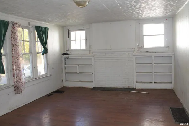 an empty room with windows and cabinet