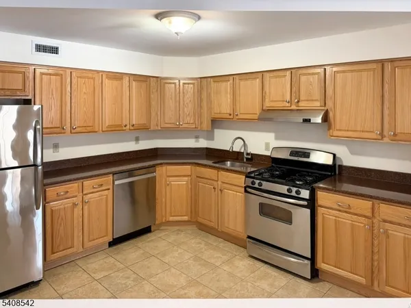 a kitchen with stainless steel appliances granite countertop a stove a sink and white cabinets