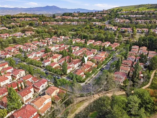 a view of sign board with yard and buildings in the background