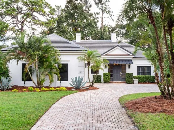 a front view of a house with a yard and potted plants
