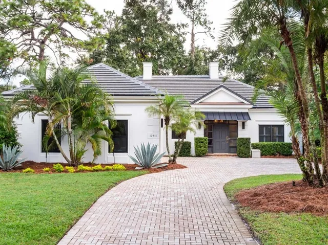 a front view of a house with a yard and potted plants