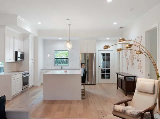 a view of kitchen with stainless steel appliances kitchen island granite countertop a refrigerator a stove top oven a sink dishwasher and white cabinets with wooden floor