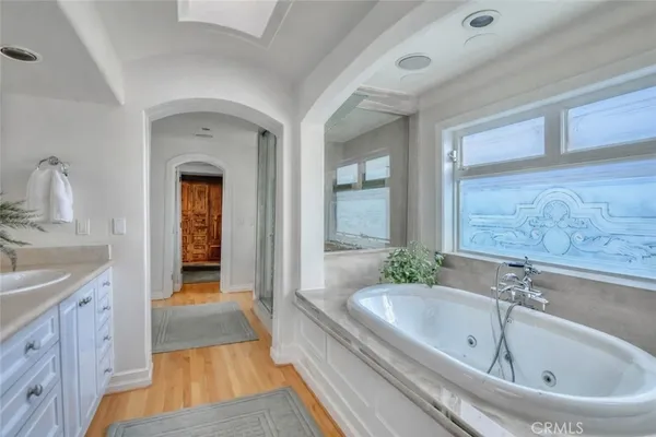 a spacious bathroom with a tub a sink and a large mirror
