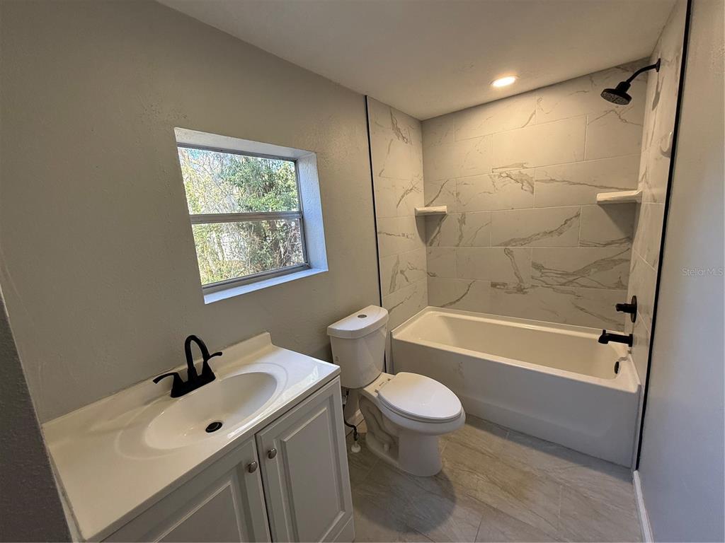 1205 Dell Street Starke, FL 32091 - Photo 9 of 12 a bathroom with a bathtub shower sink mirror vanity and toilet