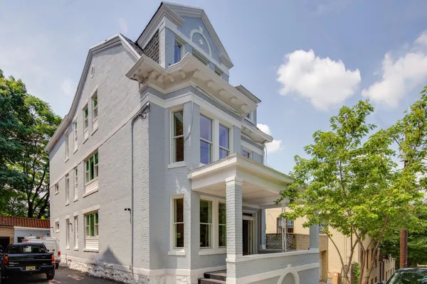 a view of a white house with a large windows and a tree