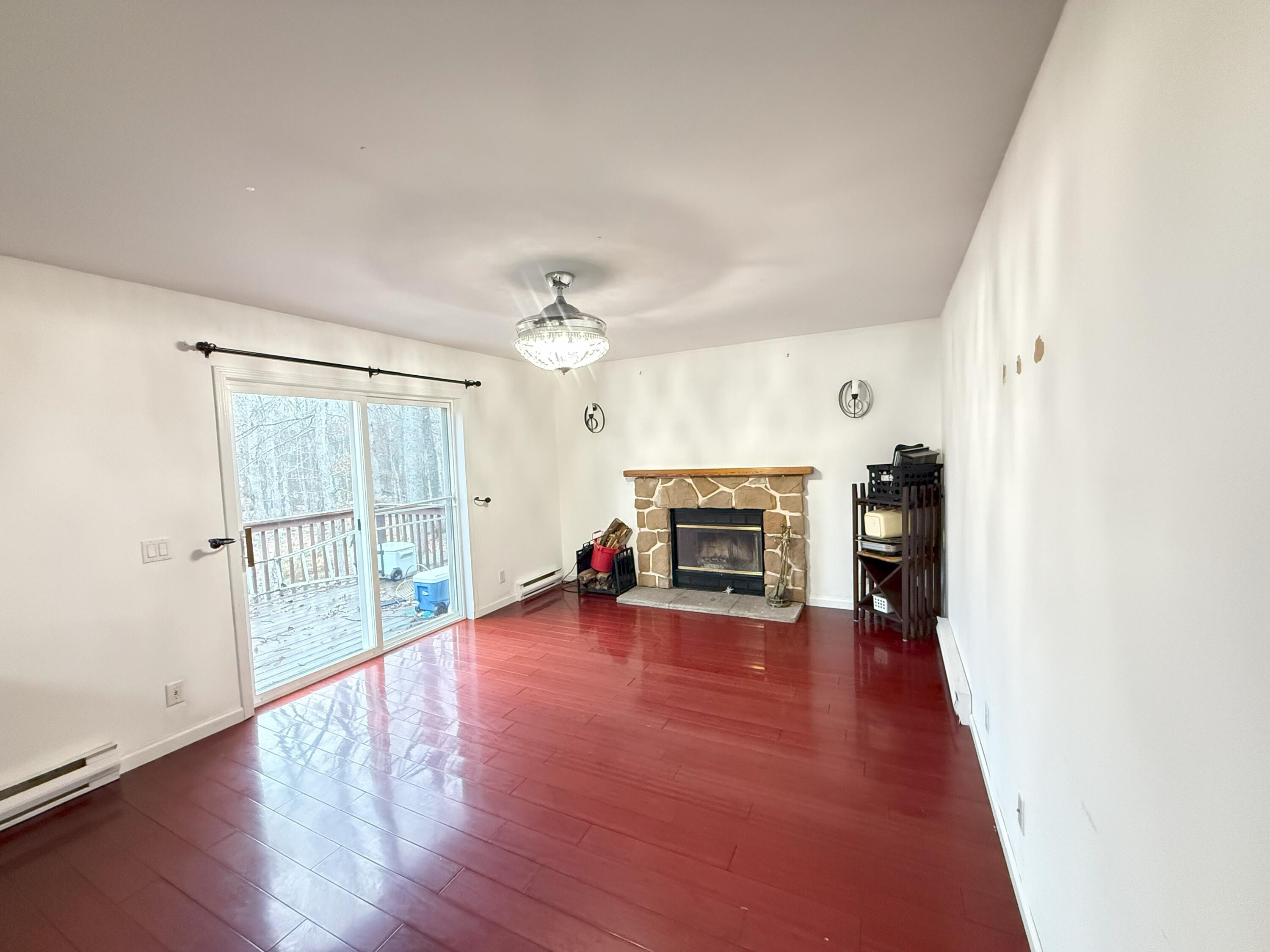 6486 Decker Road Bushkill, PA 18324 - Photo 8 of 53 an empty room with wooden floor fireplace and windows