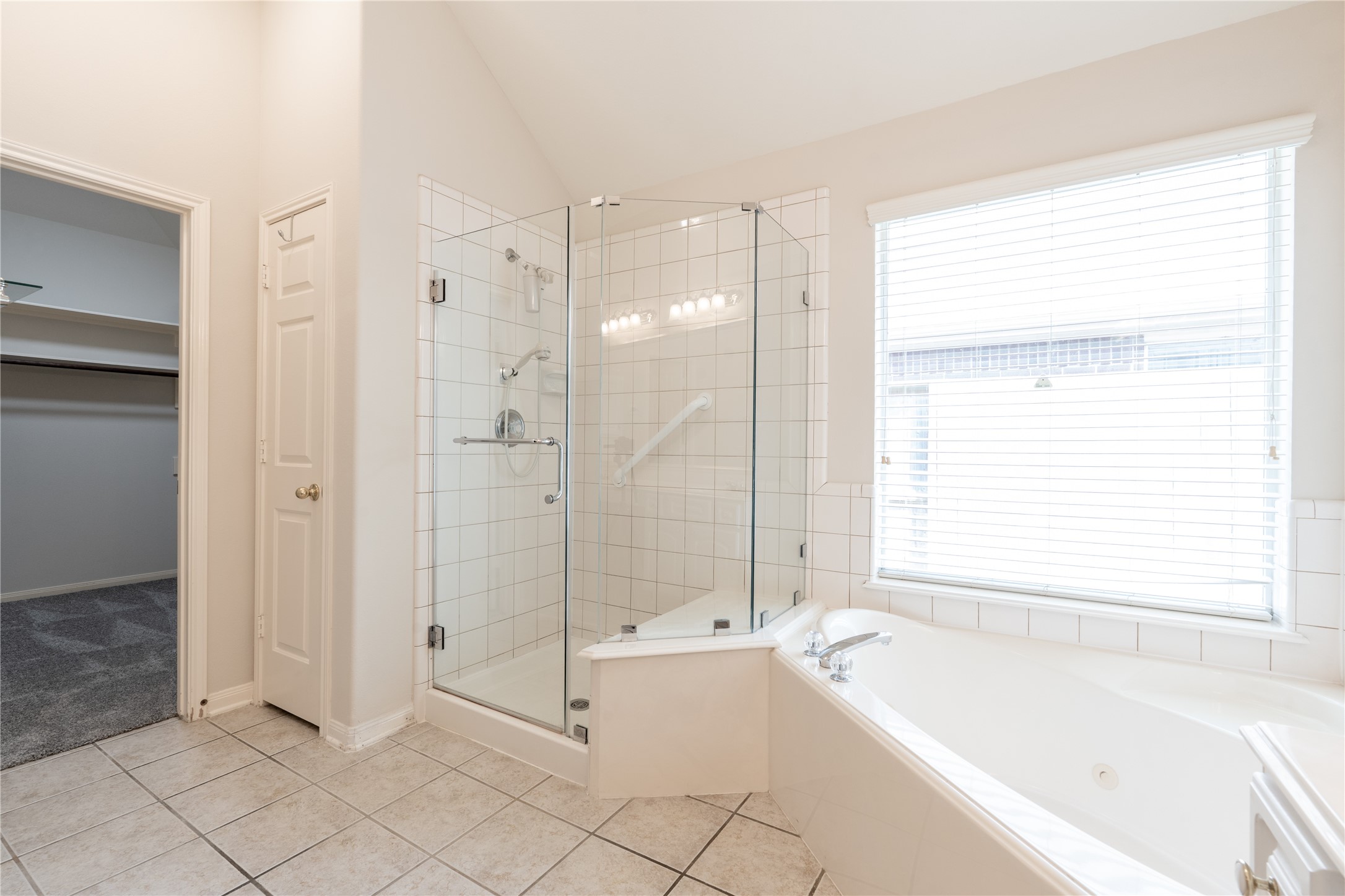 10619 Crownsedge Drive Spring, TX 77379 - Photo 15 of 38 This bright primary bathroom features a spacious walk-in shower with glass doors, a large corner bathtub, and a window for natural light. It also has access to the walk-in closet.