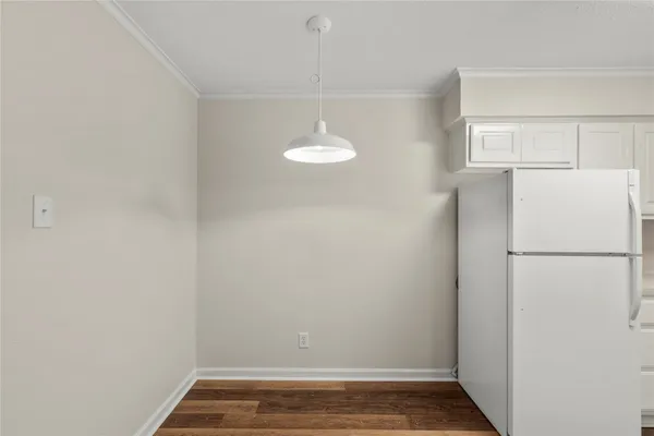 a view of a refrigerator in kitchen and an empty room