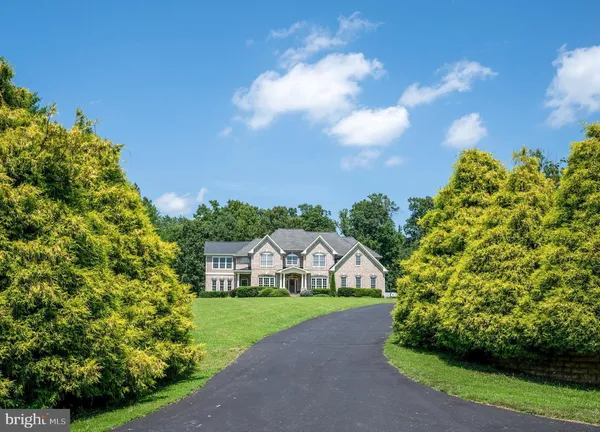 a view of a house with a big yard plants and large trees