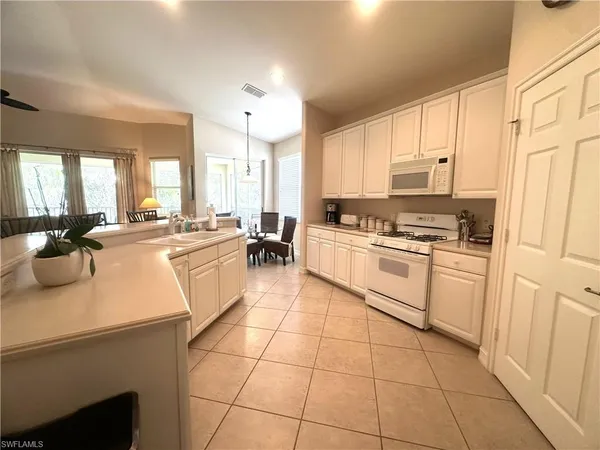 a large white kitchen with a stove a sink a microwave and cabinets
