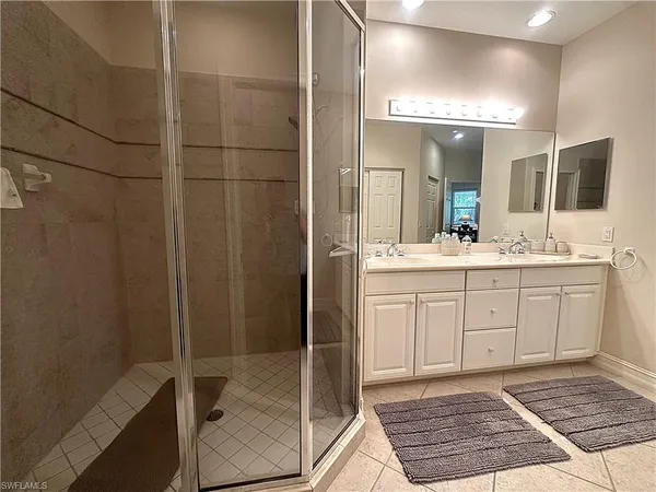 a spacious bathroom with a shower a sink and a mirror