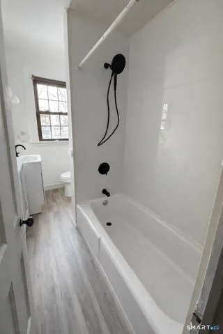 a bathroom with a bathtub a window and a shower
