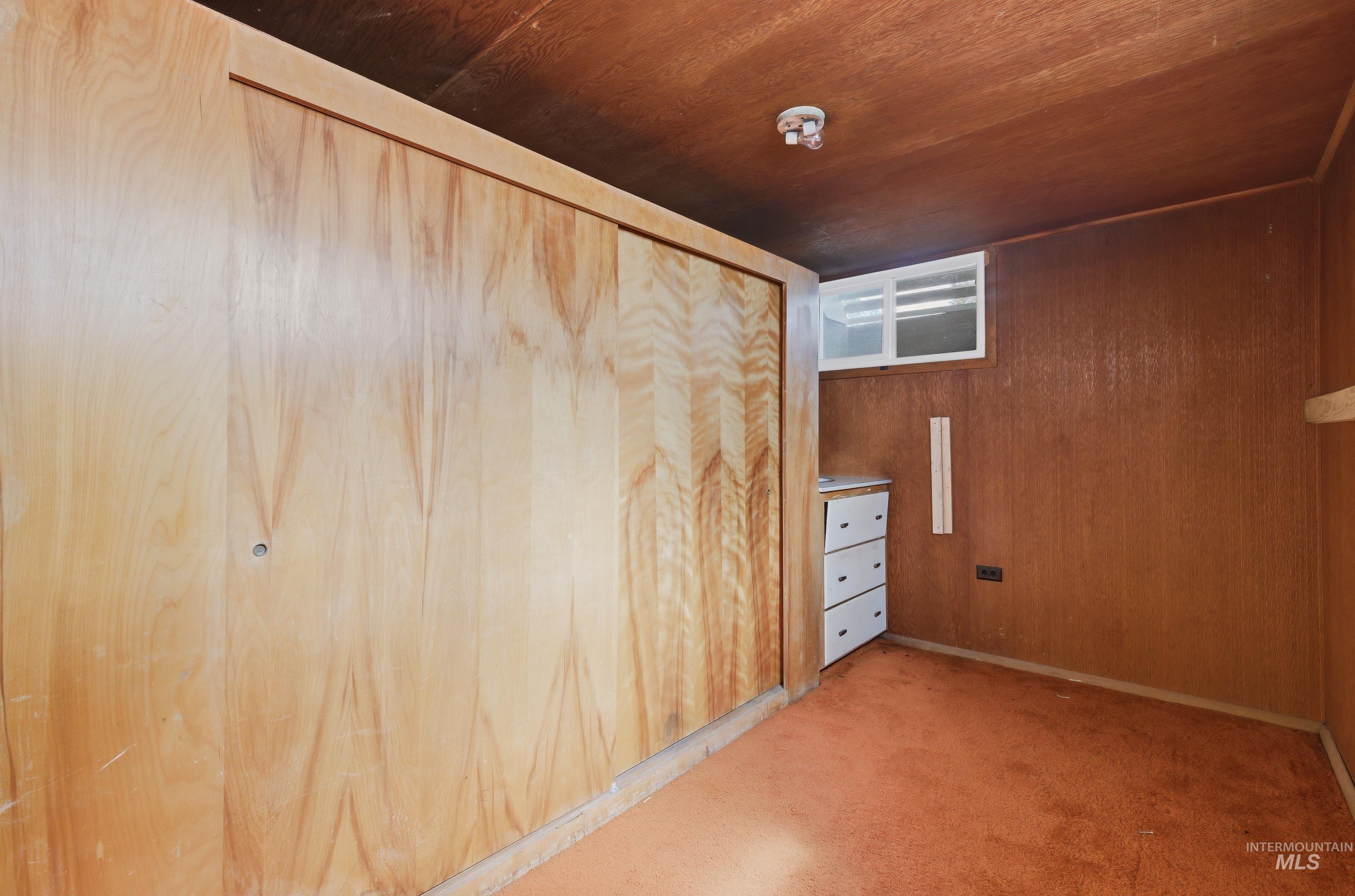 504 West Howe Street Boise, ID 83706 - Photo 31 of 47 Wood-paneled wall with sliding closet doors, featuring a built-in three-drawer cabinet and a small, high-set window