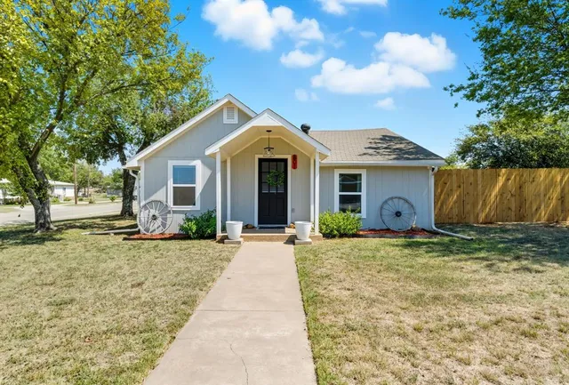 a front view of a house with a garden and tree
