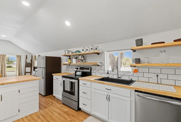 a kitchen with cabinets stainless steel appliances and wooden floor