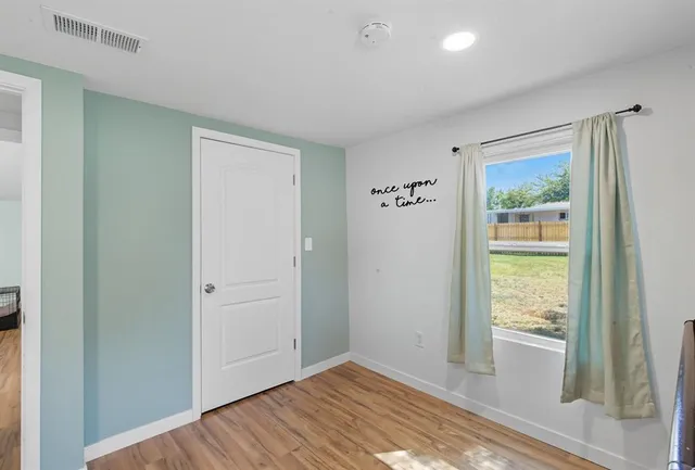 a view of hallway with window and wooden floor