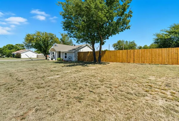a view of yard with large tree and wooden fence
