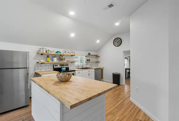 a kitchen with kitchen island a sink a refrigerator and wooden floor