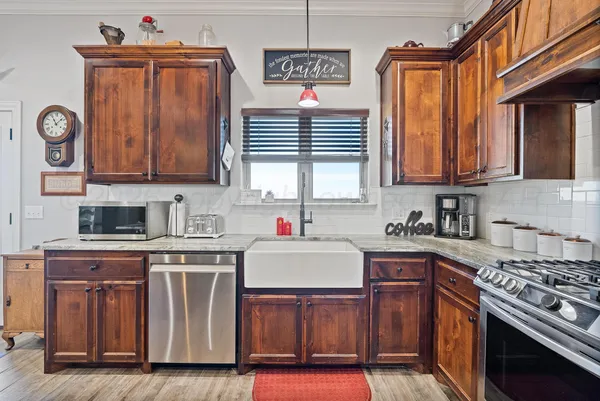 a large kitchen with stainless steel appliances kitchen island granite countertop a refrigerator a stove a sink a dining table and chairs with wooden floor