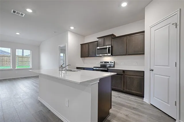 a kitchen with kitchen island granite countertop a sink cabinets and stainless steel appliances