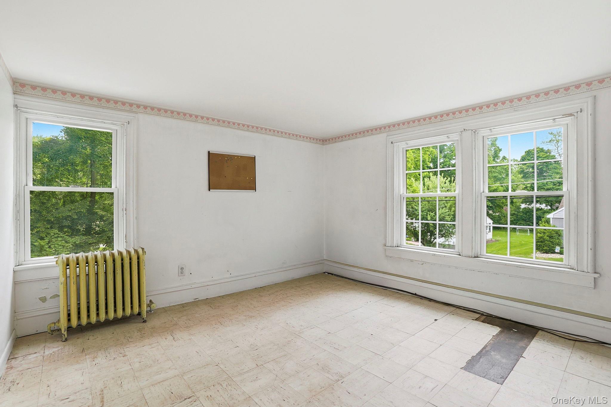 16 Hornbeck Road Poughkeepsie, NY 12603 - Photo 6 of 10 Room featuring multiple windows, a radiator, and a decorative border